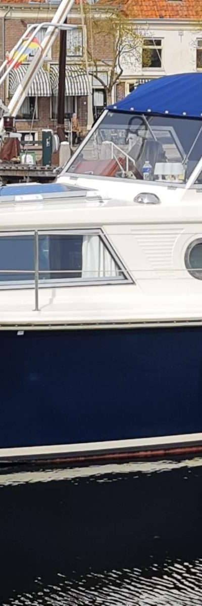 Wit met donkerblauwe romp en blauwe cabriokap, in een gracht.
