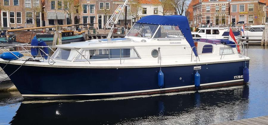 Wit met donkerblauwe romp en blauwe cabriokap, in een gracht.