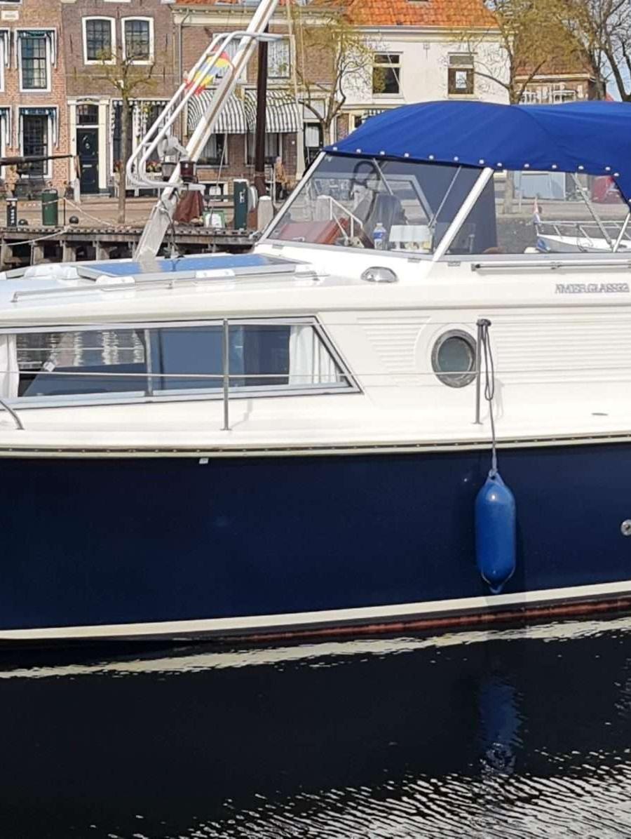 Wit met donkerblauwe romp en blauwe cabriokap, in een gracht.