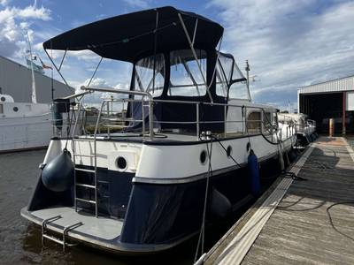 Jacht aangemeerd, blauw-wit, met bimini en zwemplateau. Mooi weer.