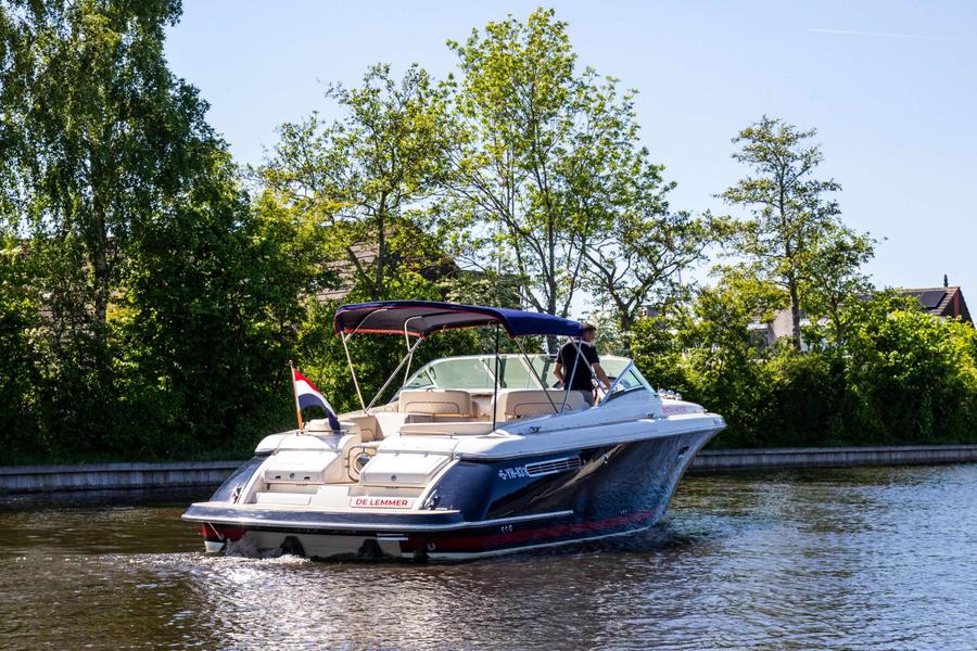 Blauwe boot met beige interieur vaart op water, groen omzoomd.