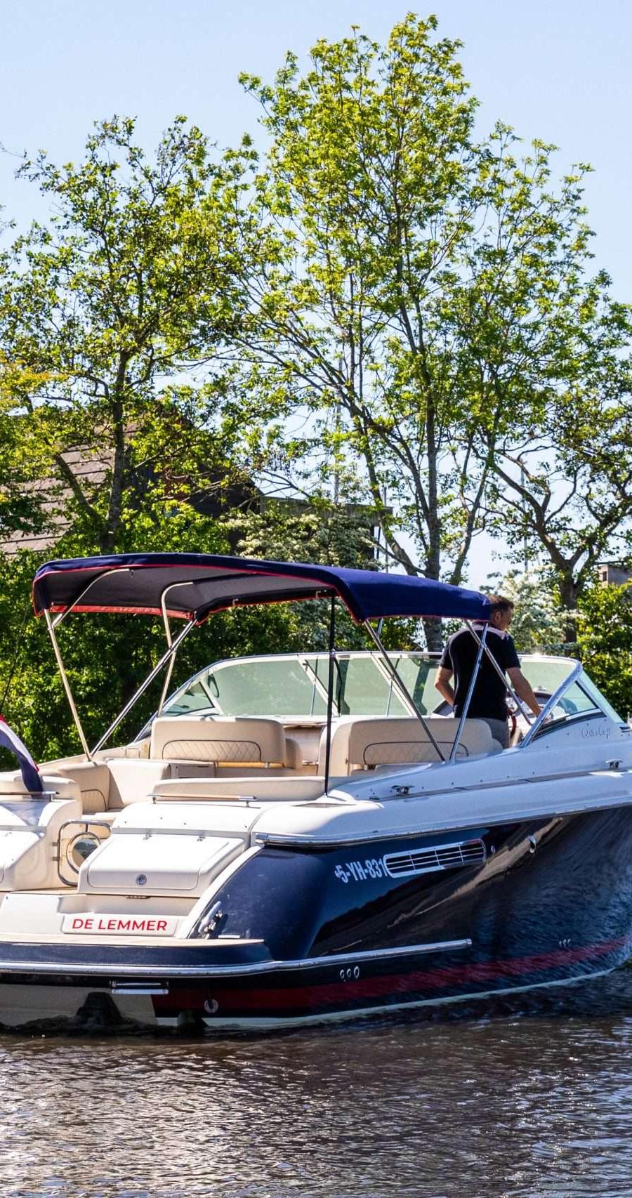 Blauwe boot met beige interieur vaart op water, groen omzoomd.