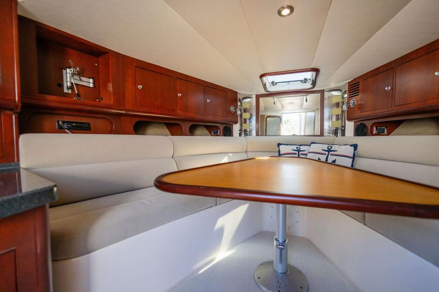 Interieur met U-vormige dinette, houten tafel, kussens en opbergkasten.