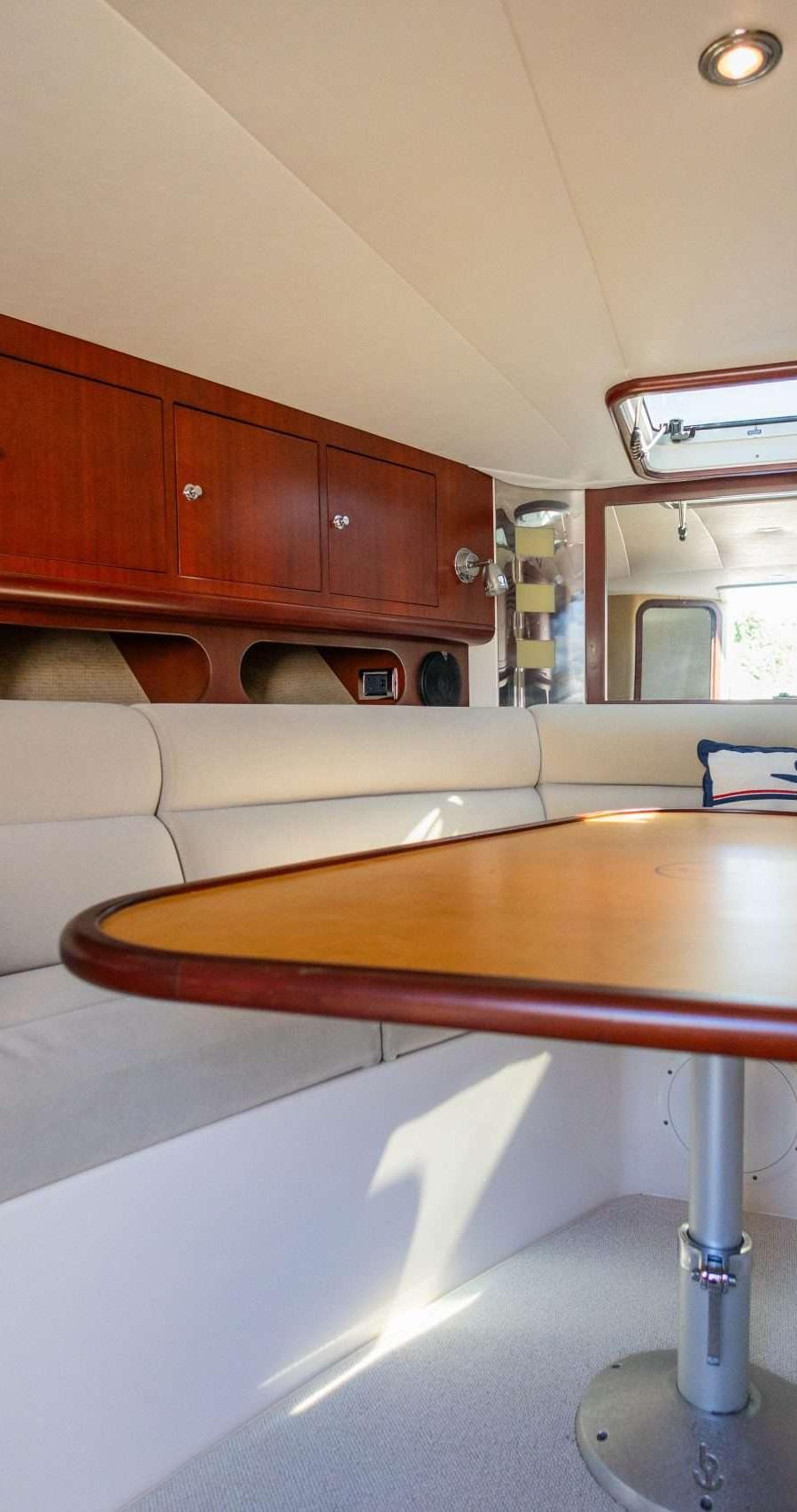 Interieur met U-vormige dinette, houten tafel, kussens en opbergkasten.