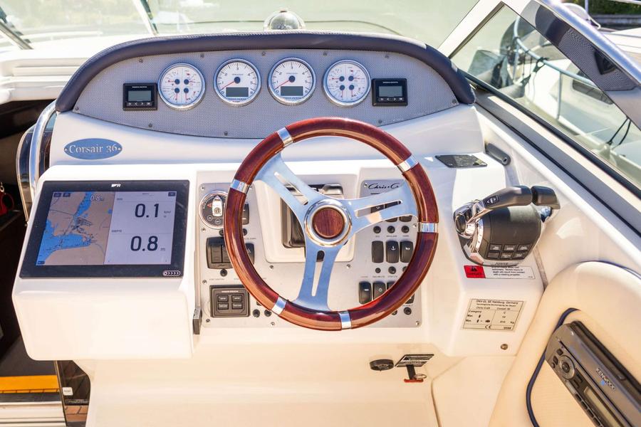 Stuurconsole met houten stuurwiel, navigatiescherm, meters en bedieningsknoppen.