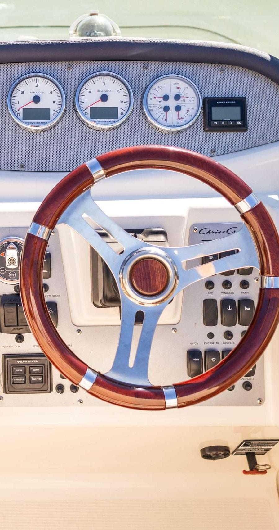 Stuurconsole met houten stuurwiel, navigatiescherm, meters en bedieningsknoppen.