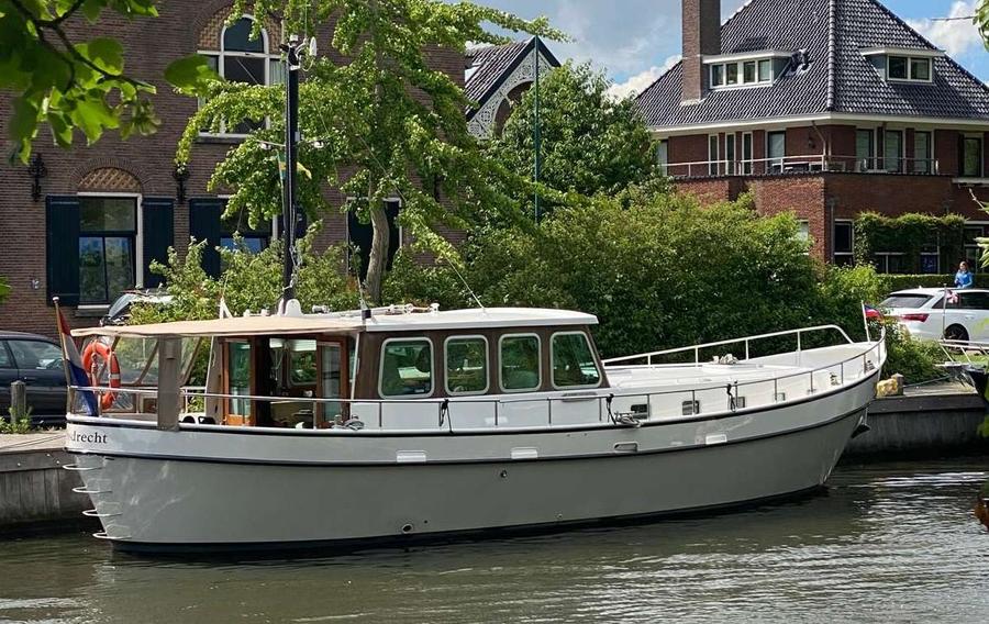 Stalen motorjacht met open kuip, liggend aan een kade.
