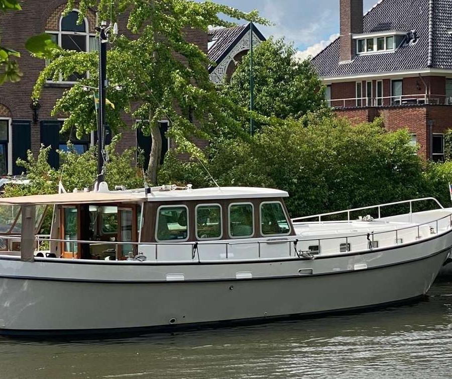 Stalen motorjacht met open kuip, liggend aan een kade.