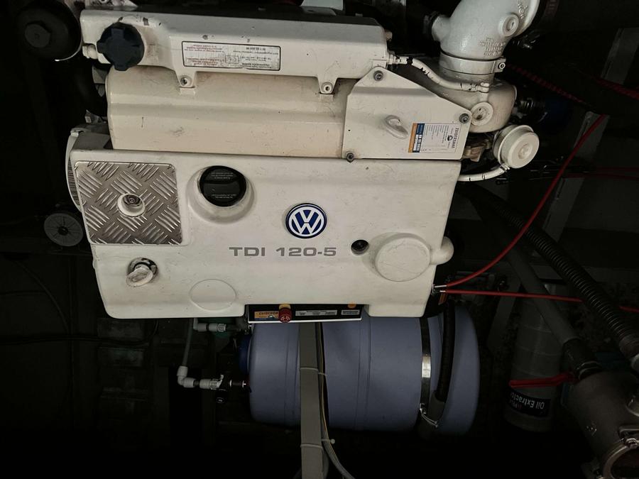 Motorruimte met witte motor, diverse leidingen en een boiler.