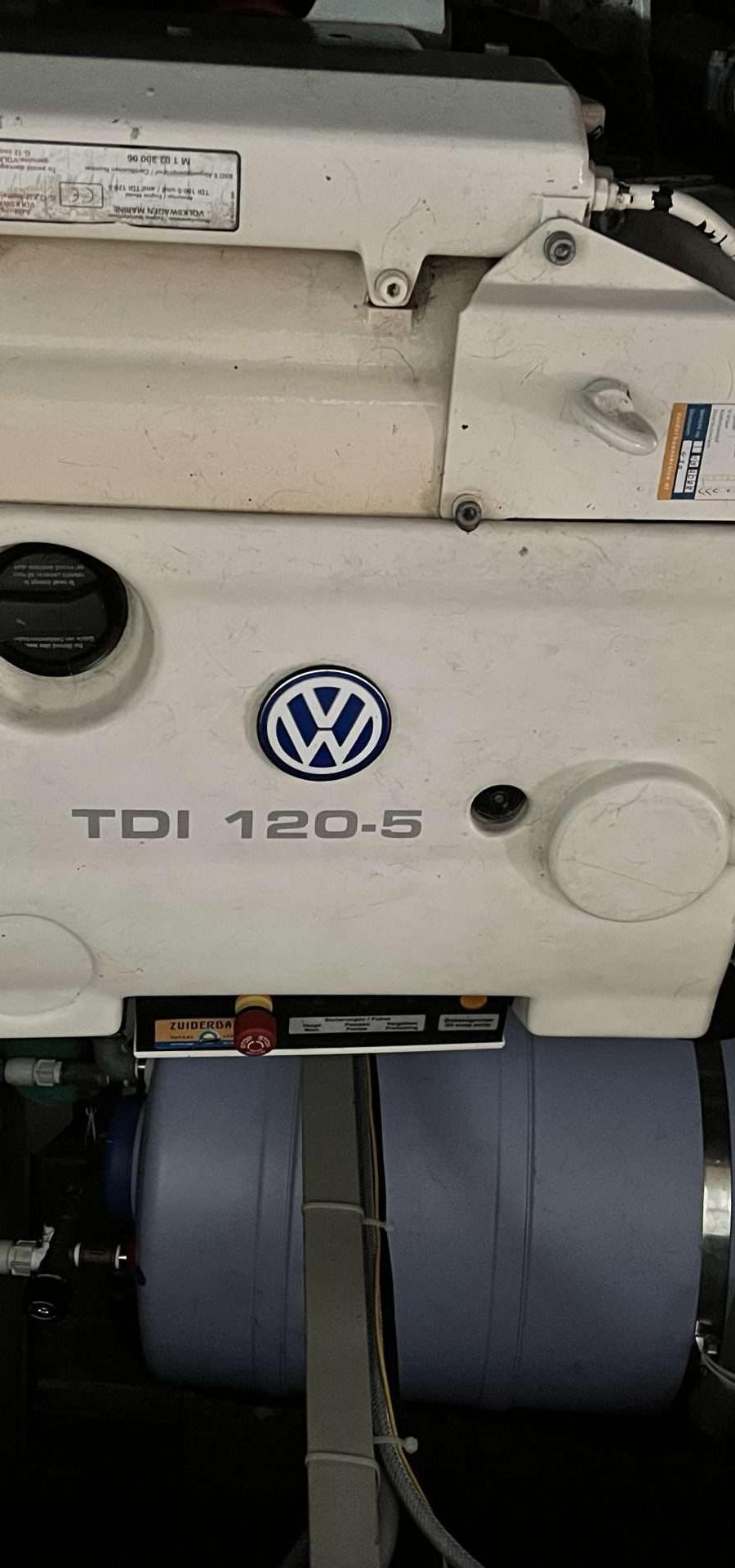Motorruimte met witte motor, diverse leidingen en een boiler.