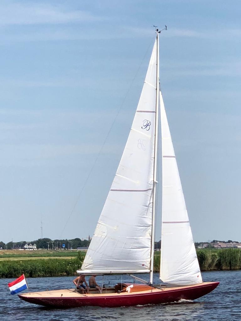 Ed Dubois Bolero - zeilboot met witte zeilen en rode romp aan bakboord