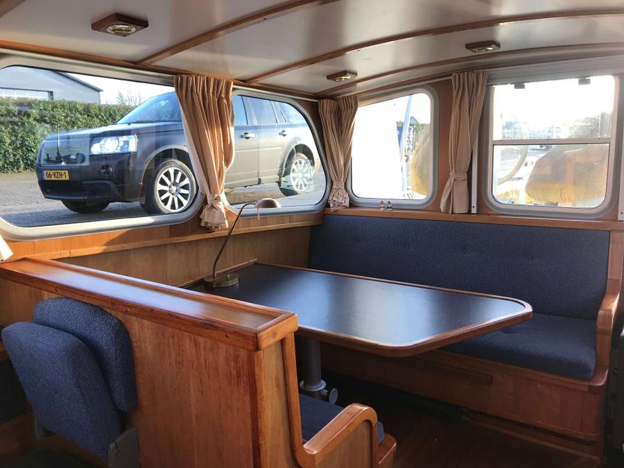 Voormalige Patrouilleboot - Salon met zithoek en tafel, ramen met gordijnen